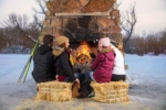 4 people gathered around outside fireplace sitting on haybales